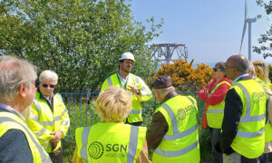 A man in PPE talking to a group of people in PPE