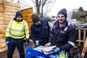 Three men standing together looking at instructions